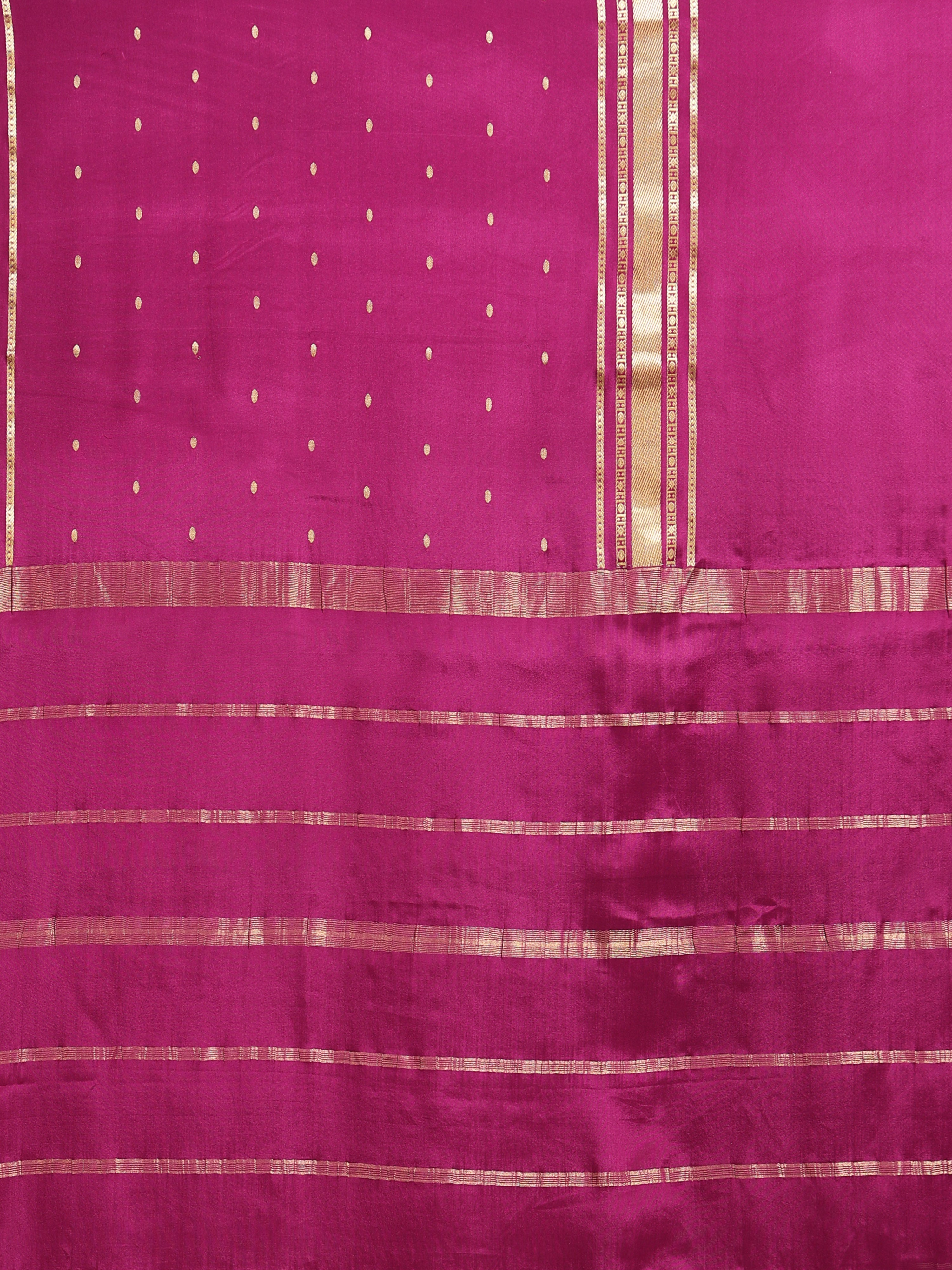 Close up of rani pink body with scattered oval gold zari buttas and horizontal stripe pallu bands