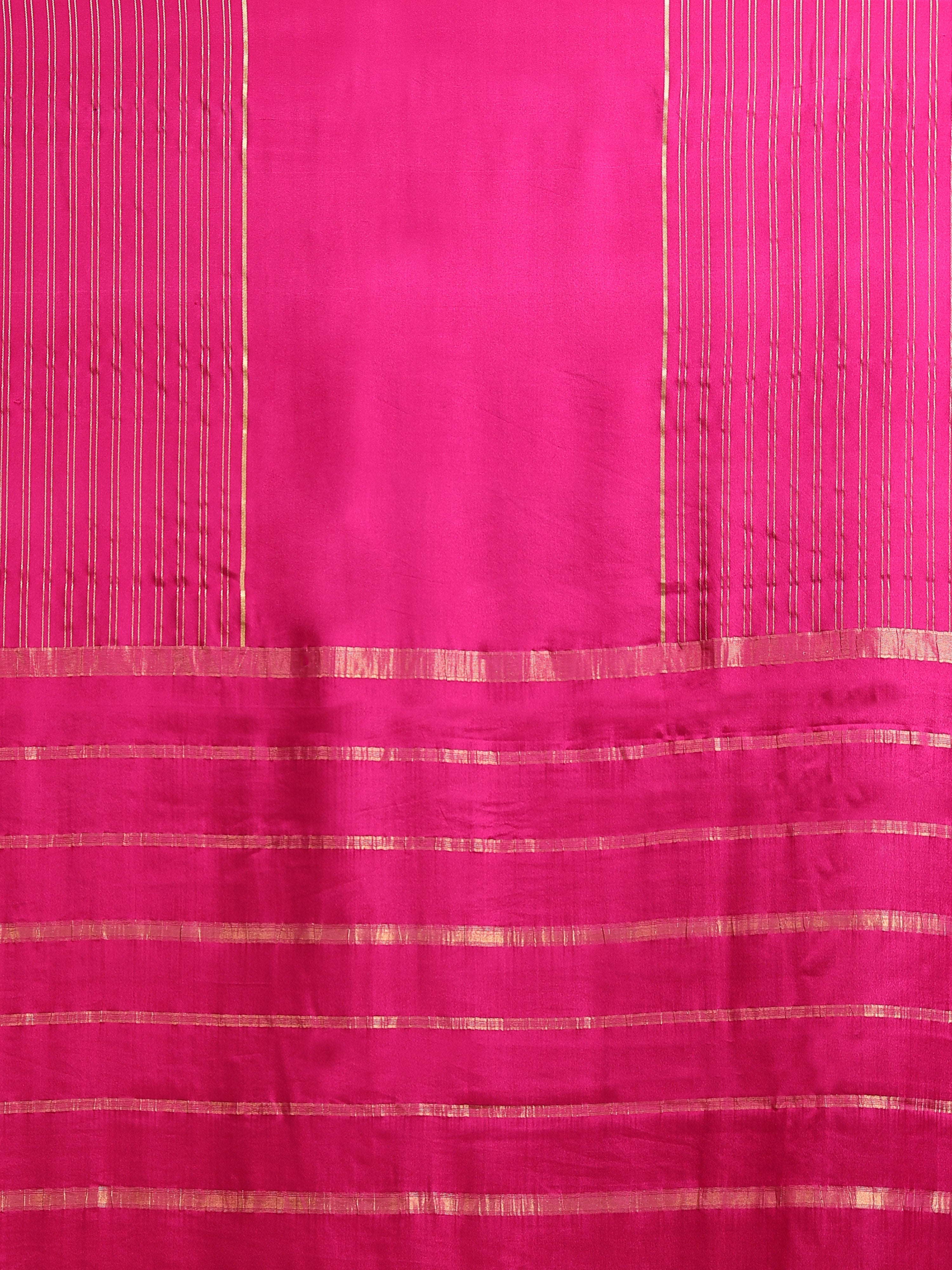 Close up of fuchsia body with fine vertical gold zari stripes and horizontal stripe pallu bands