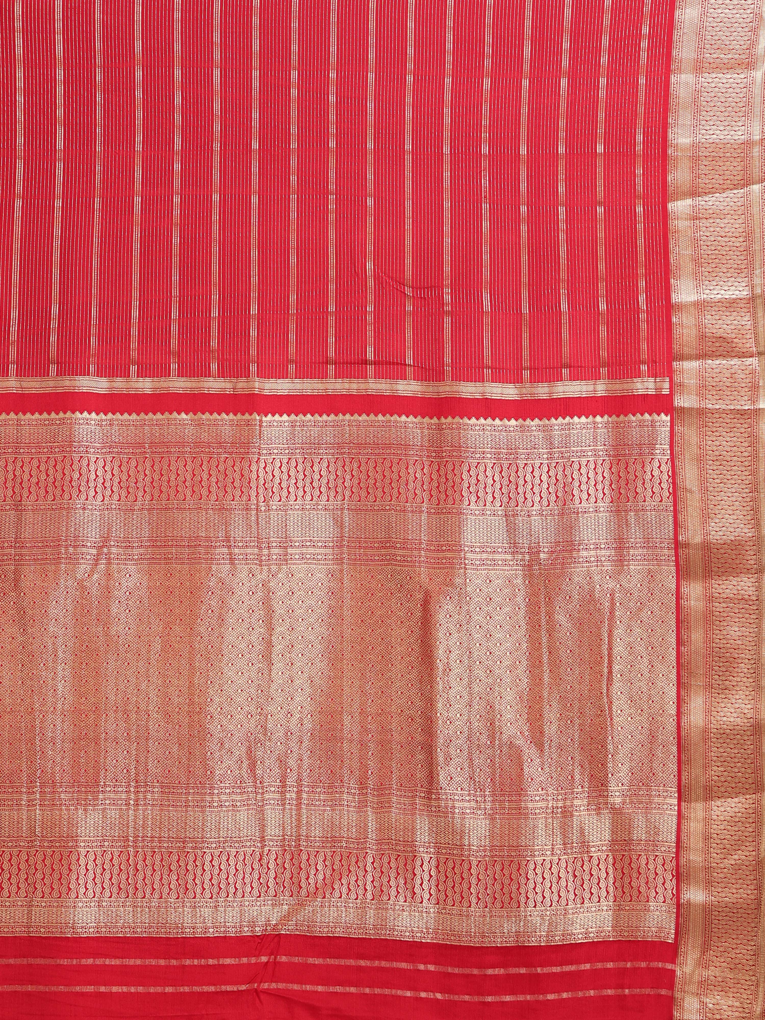 Close up of coral red body with dense fine vertical gold zari stripes and all-over gold jaal pallu with wave border bands