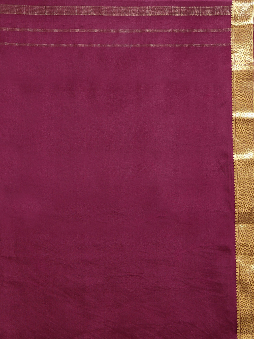 Close up of plain burgundy silk body with natural lustre and wide antique gold zari diamond chevron geometric border