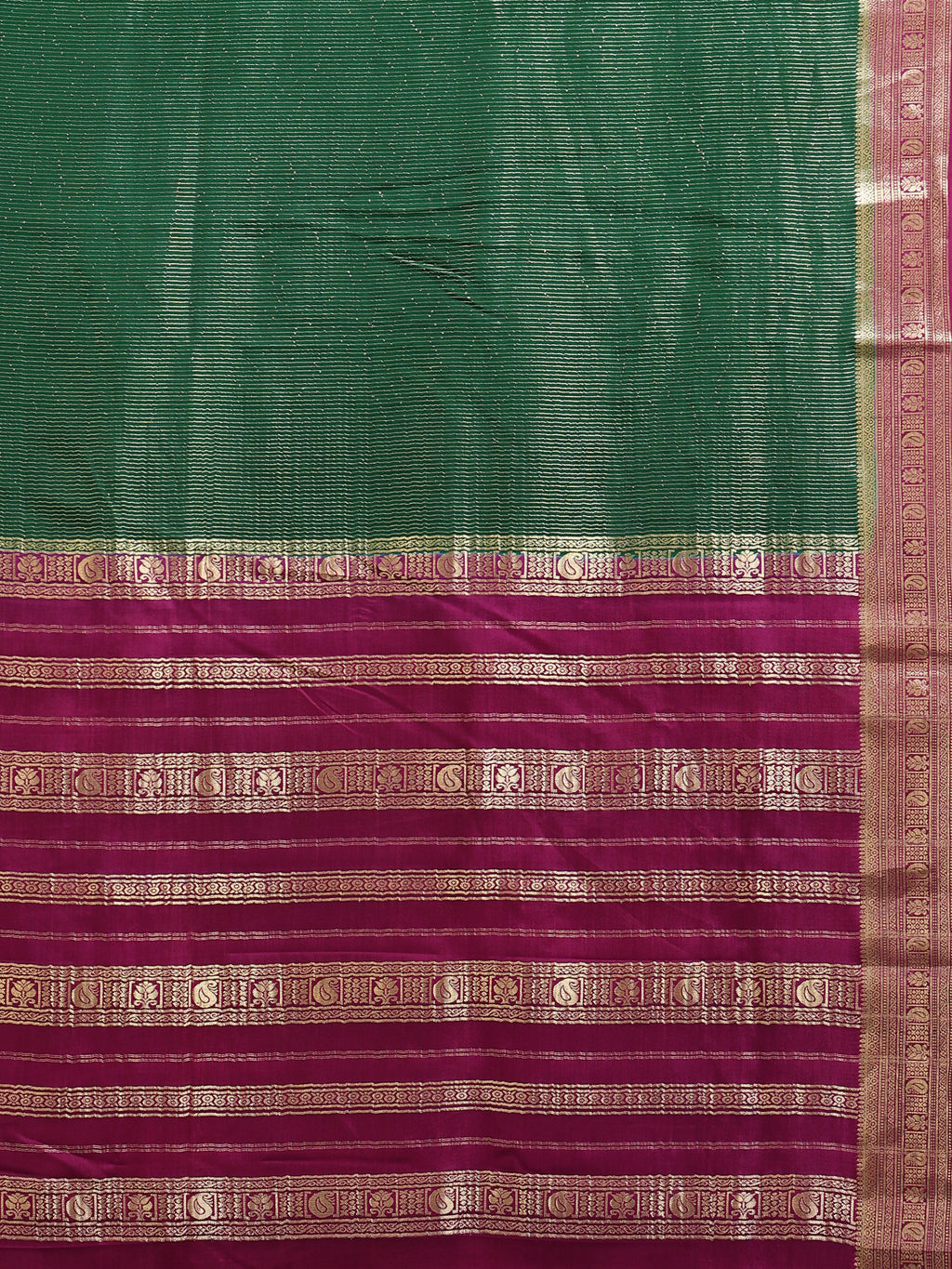 Close up of bottle green body with fine horizontal gold zari stripes and deep magenta pallu with gold zari peacock bands