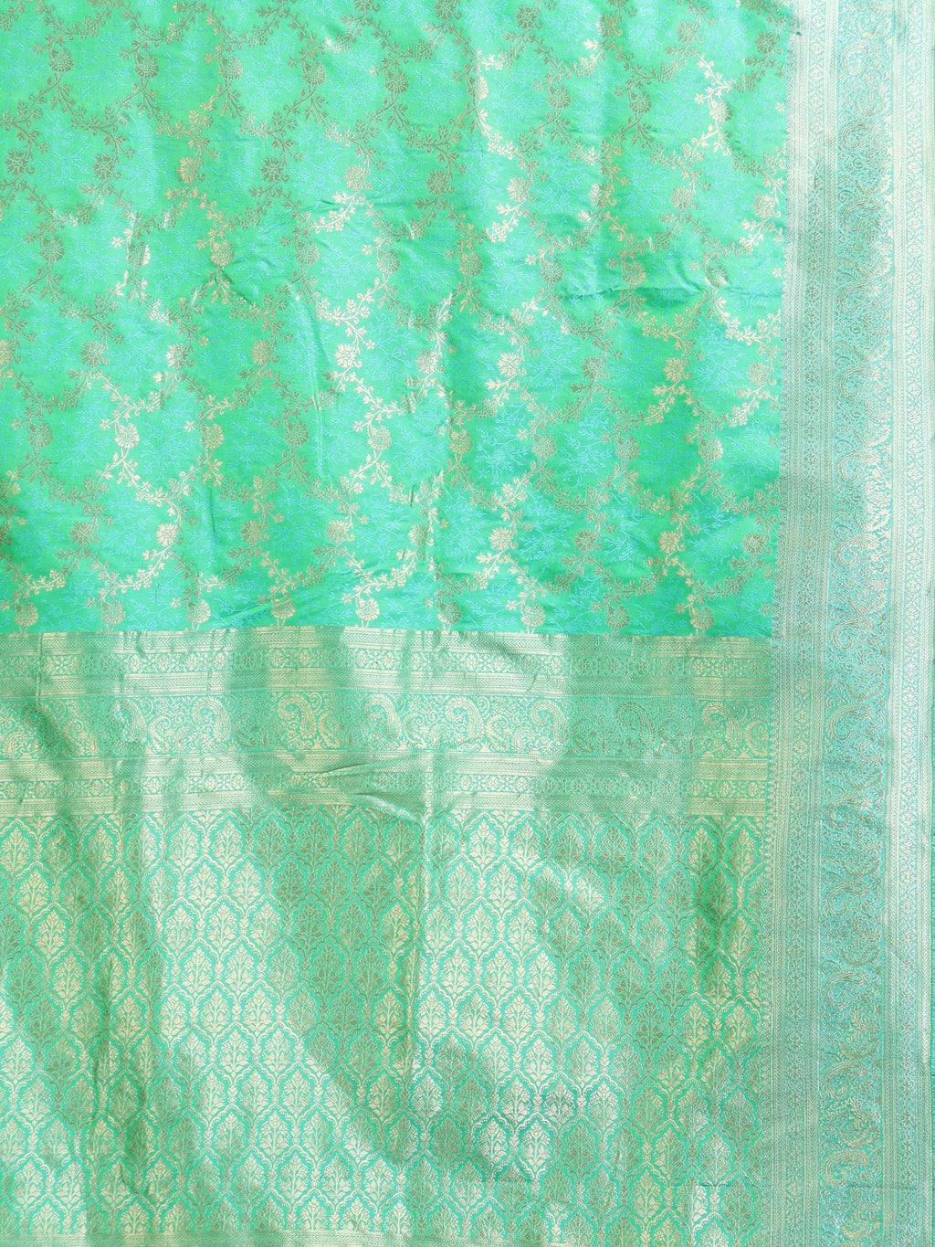Close up of mint green body with dense continuous silver zari floral vine creeper jaal and all-over silver zari ogee arch lattice pallu